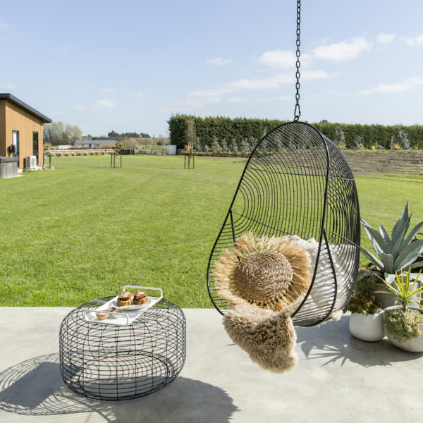 Outdoor wire furniture. A black wire ottoman with a black wire hanging chair.
