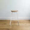 back view of kitchen stool with white wire legs & a round solid oak seat