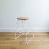 angle view of kitchen stool with white wire legs & a rounded solid oak seat