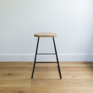 front view of kitchen barstool with black wire legs & organically rounded solid oak seat