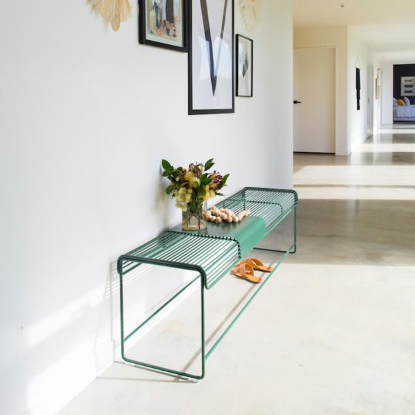 Wire bench seat with movable metal plate, sitting in a sunny hallway.