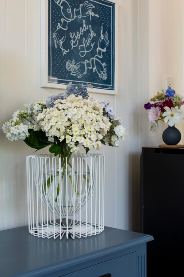 Hydrangeas sitting in a white wire plant holder