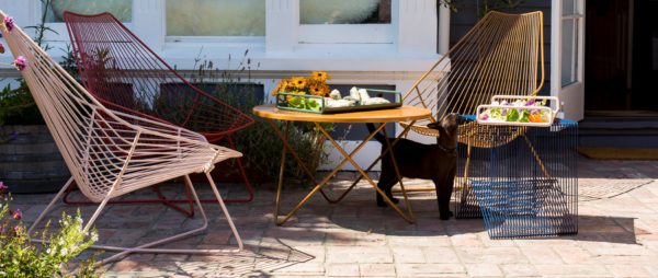 Outdoor furniture setting with mid century inspired wire chairs, table, side table.