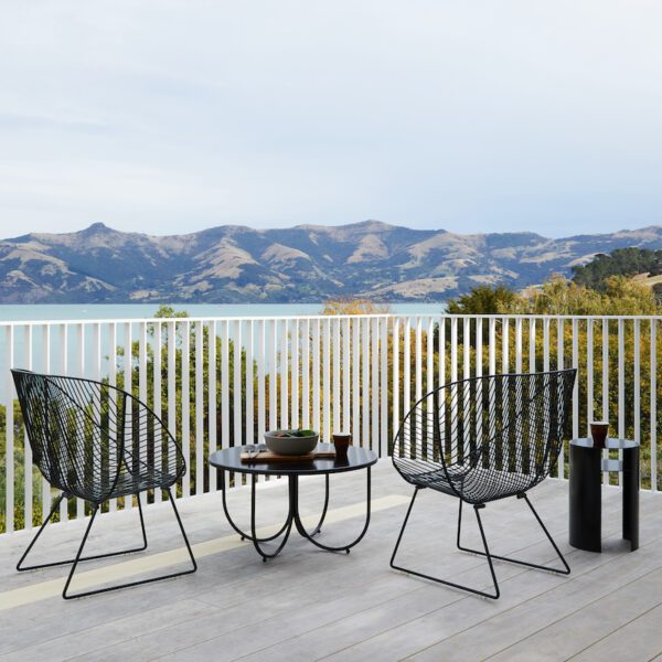 Stainless steel outdoor lounge chair with wide seat and curved wire design, styled for comfort and durability in coastal environments.