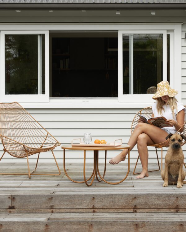 Woman relaxing with her dog on Ico Traders wire chairs and table set in toffee colourway on a wooden deck.