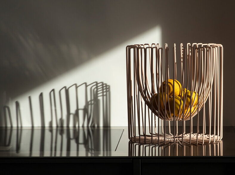 Ico Traders wire fruit bowl in soft neutral finish with lemons, modern New Zealand homewares styling on black cabinet.